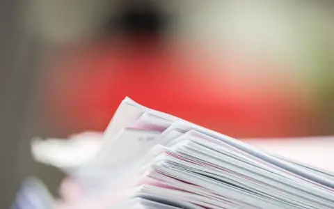Stos dokumentów, potencjalne dowody rzeczowe w postępowaniu karnym, z czerwonym tłem.