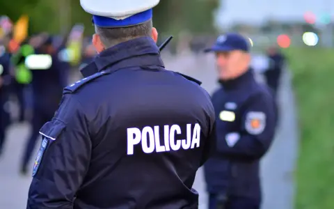 Policjanci w mundurach, jeden z napisem "POLICJA" na plecach, gotowi do akcji. Czy to kontrola osobista, czy przeszukanie?