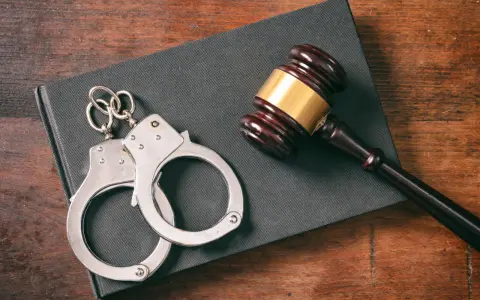 Kajdanki i młotek sędziowski na księdze. Zastanawiasz się, ile grozi za zabicie człowieka? Prawo jest surowe.