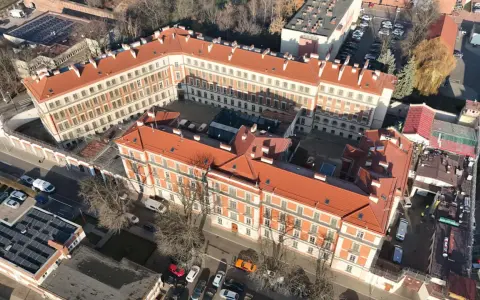 Widok z lotu ptaka na zakład karny Montelupich. Widać budynki z czerwonymi dachami, ogrodzenie z drutem kolczastym i parking. Odwiedziny w zakładzie karnym.
