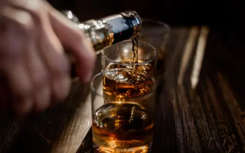 Nalewanie alkoholu do szklanek. Ta scena może symbolizować sprawę w sądzie za picie alkoholu przez nieletnich.