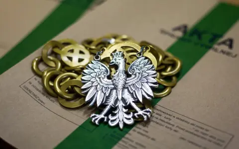 Srebrny orzeł na złotym łańcuchu, leżący na aktach. Symbolizuje prekluzja dowodowa w polskim prawie.