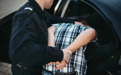 Policjant zakłada kajdanki zatrzymanemu młodemu mężczyźnie. Od ilu lat ponosi się odpowiedzialność karna?