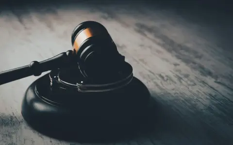 Młotek sędziowski i kajdanki na drewnianym blacie. Symbol sprawiedliwości i prawa, być może środek zaskarżenia.