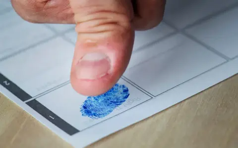 Kciuk z niebieskim odciskiem palca na papierze. Czy to początek śledztwa, czy tylko rutynowa procedura? Jak długo można być podejrzanym?