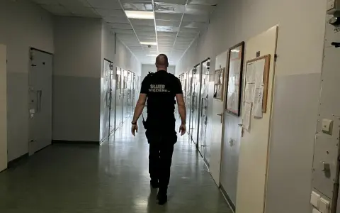Strażnik więzienny idzie korytarzem, gdzie odbywa się klasyfikacja skazanych. Wzdłuż korytarza znajdują się cele.