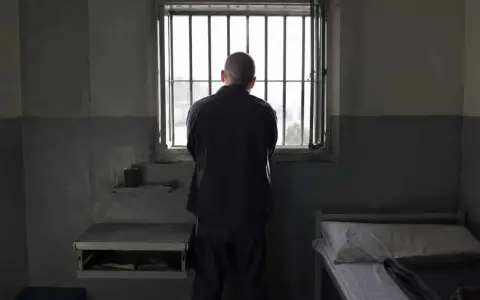 Samotny więzień patrzy przez kraty okna. To obraz odzwierciedlający cele wykonywania kary pozbawienia wolności: izolację i refleksję.