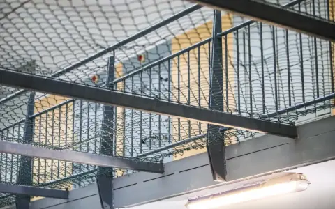 Wnętrze więzienia z siatką zabezpieczającą i prętami, które mogą przypominać, jak wygląda wezwanie do więzienia.