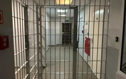 Korytarz więzienny z kratami, gdzie każdy krok może prowadzić do spotkania z niebezpiecznym więźniem.