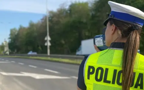 Policjantka w kamizelce odblaskowej mierzy prędkość pojazdów. Uważaj na tryb przyspieszony na drodze!