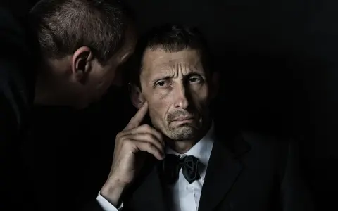 Mężczyzna w garniturze słucha szeptanych tajemnic. Czy to zasada omerty?