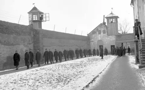 Więźniowie w mroźny dzień na dziedzińcu jednego z najcięższych więzień w Polsce. Strażnicy obserwują z wieżyczek.