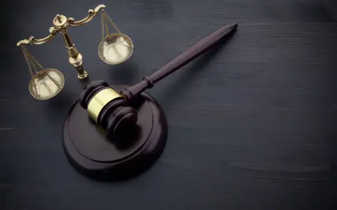 Młotek sędziowski i waga sprawiedliwości na ciemnym tle. Symbolizują sprawiedliwość i prawo, a także mogą oznaczać zmianę miejsca wykonywania prac społecznych.