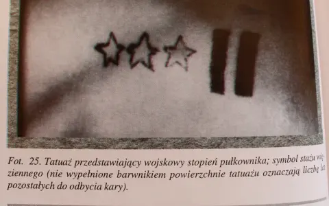 Trzy gwiazdy i dwie pionowe kreski – tatuaże więzienne, symbolizujące stopień wojskowy i czas pozostały do odbycia kary.