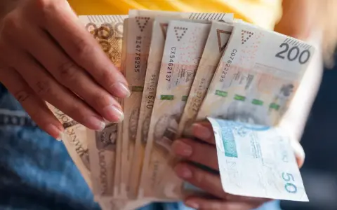 Dłonie trzymają plik banknotów 200 zł i 50 zł. Jak egzekwować obowiązek naprawienia szkody, gdy sprawca nie chce zapłacić?
