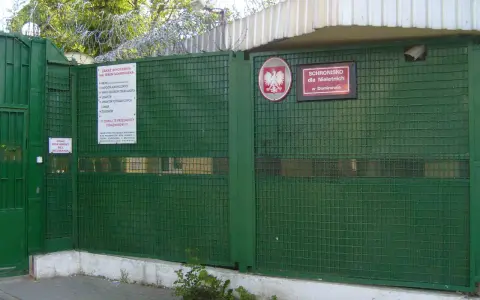 Zielona brama z drutem kolczastym i znakiem "Schronisko dla Nieletnich w Dominowie". To miejsce, gdzie młodzież potrzebuje wsparcia, a nie kary.