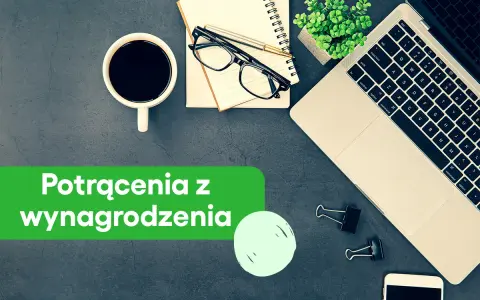 Biurko z laptopem, kawą i notatnikiem. Zielony baner informuje o potrąceniach z wynagrodzenia skazanego.