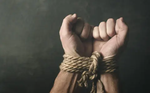 Związane dłonie, symbolizujące bezsilność i potencjalne naruszenie art. 189a kk.