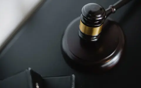 Młotek sędziowski na czarnym tle, symbol sprawiedliwości. Może symbolizować ważną decyzję, jak w przypadku pierwszego świadka koronnego w Polsce.