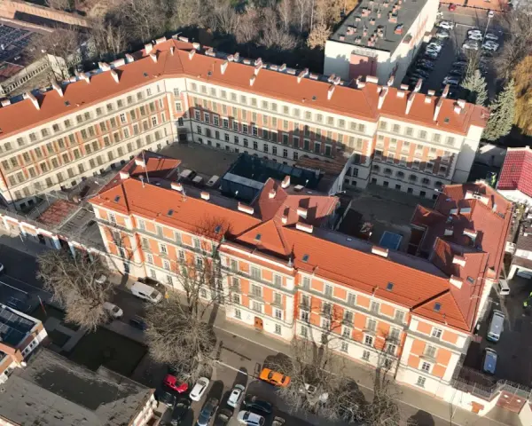 Widok z lotu ptaka na zakład karny Montelupich. Widać budynki z czerwonymi dachami, ogrodzenie z drutem kolczastym i parking. Odwiedziny w zakładzie karnym.
