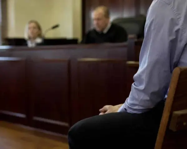 Osoba siedzi w ławie sądowej, czekając na decyzję w sprawie zgodnej z art. 37a. Sąd obraduje.