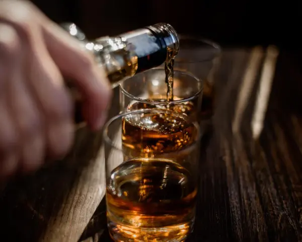 Nalewanie alkoholu do szklanek. Ta scena może symbolizować sprawę w sądzie za picie alkoholu przez nieletnich.
