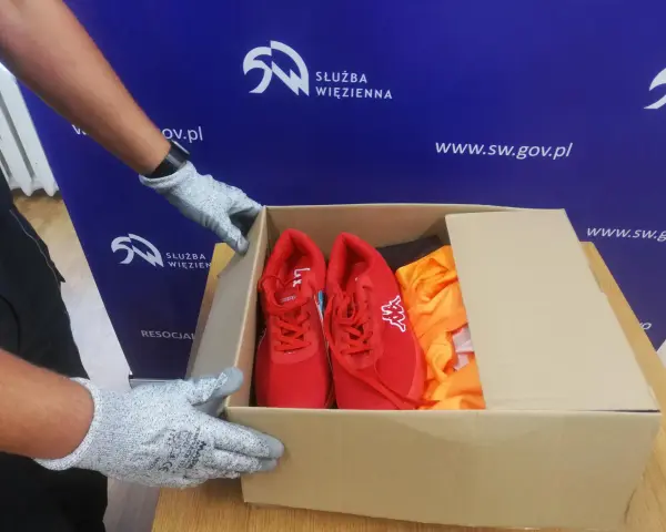 Rękawiczki przygotowują paczkę z czerwonymi butami i pomarańczową odzieżą. To wzór talonów dla osadzonych.