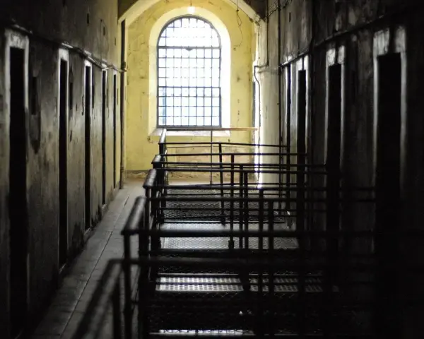 Korytarz więzienny z celami i kratami. Czekanie na decyzję sądu, po jakim czasie sąd wydaje nakaz doprowadzenia do zakładu karnego, może być długie.