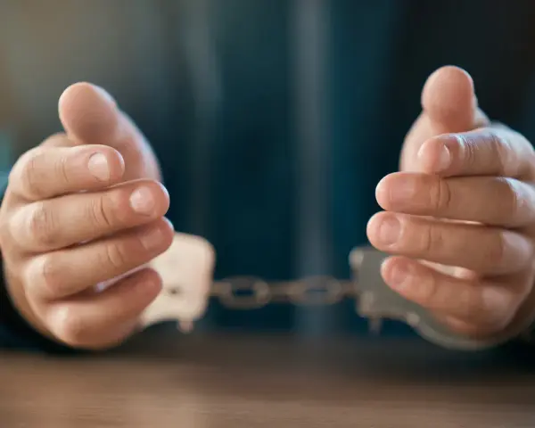Dłonie w kajdankach, symbolizujące zatrzymanie zgodnie z art. 257 kpk.