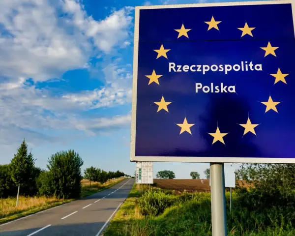 Granica Polski. Znak z gwiazdami Unii Europejskiej i napisem "Rzeczpospolita Polska". Droga prowadzi w głąb kraju, gdzie można złożyć wniosek o uchylenie zakazu opuszczania kraju.