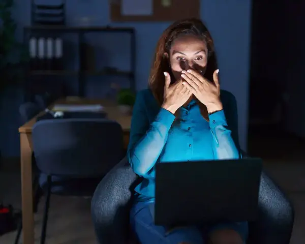 Kobieta zszokowana treścią na laptopie, czuje się jakby była obiektem prześladowania kogoś.