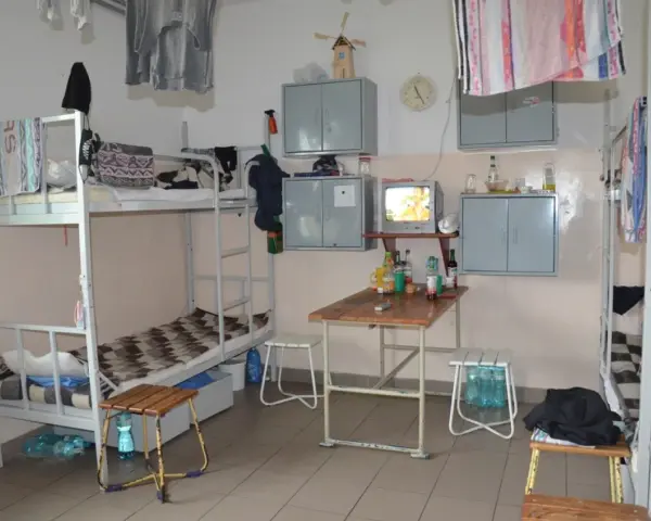 Wnętrze przypomina **zakład karny cela** z łóżkami piętrowymi, stołem, telewizorem i szafkami.