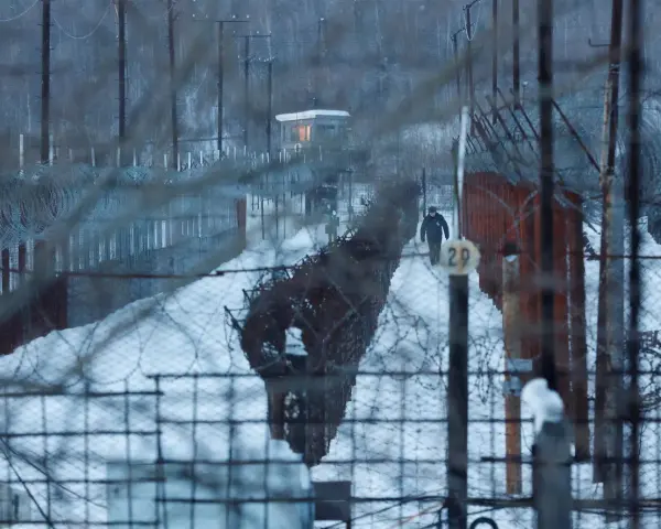 Strażnik idzie przez zaśnieżony teren otoczony drutem kolczastym. To może być najgorsze więzienie w Rosji, gdzie zimno i izolacja są częścią kary.