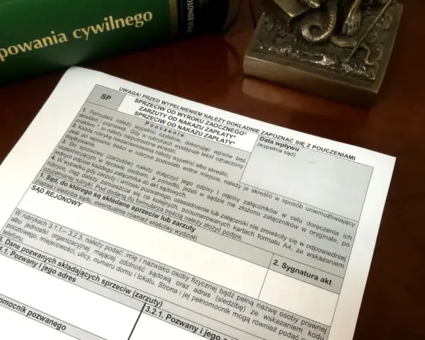 Dokument z pouczeniami do wypełnienia sprzeciwu od wyroku zaocznego lub nakazu zapłaty, obok zielonej księgi "Kodeks postępowania cywilnego".