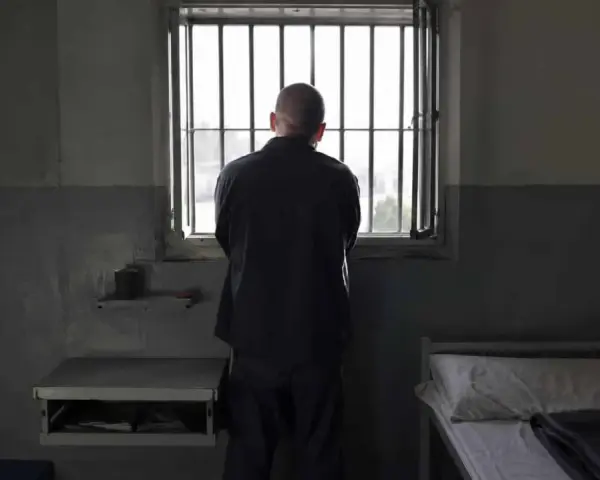 Samotny więzień patrzy przez kraty okna. To obraz odzwierciedlający cele wykonywania kary pozbawienia wolności: izolację i refleksję.