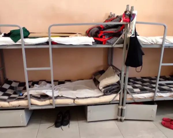 Tak wygląda dzień w areszcie śledczym: piętrowe łóżka, koce, poduszki i buty na podłodze.