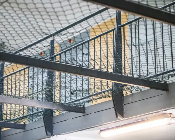 Wnętrze więzienia z siatką zabezpieczającą i prętami, które mogą przypominać, jak wygląda wezwanie do więzienia.