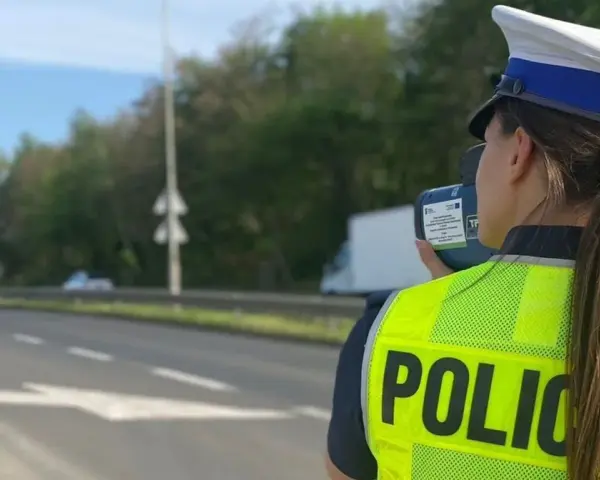 Policjantka w kamizelce odblaskowej mierzy prędkość pojazdów. Uważaj na tryb przyspieszony na drodze!