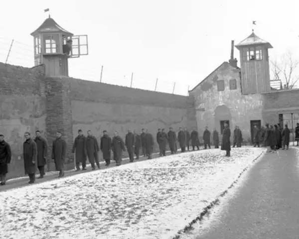 Więźniowie w mroźny dzień na dziedzińcu jednego z najcięższych więzień w Polsce. Strażnicy obserwują z wieżyczek.