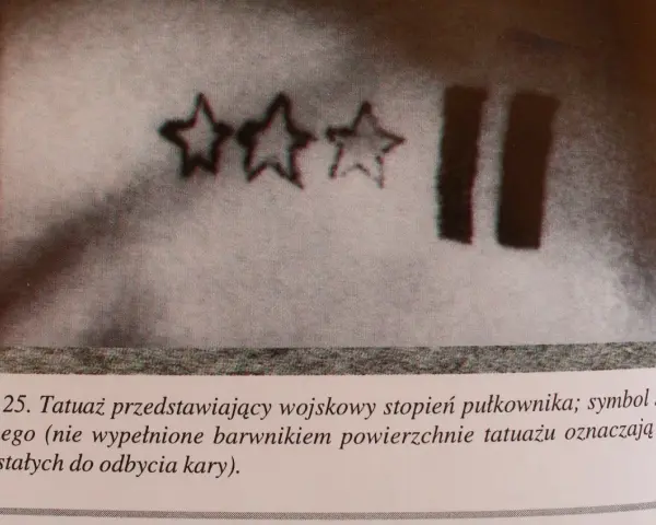 Trzy gwiazdy i dwie pionowe kreski – tatuaże więzienne, symbolizujące stopień wojskowy i czas pozostały do odbycia kary.