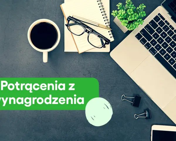 Biurko z laptopem, kawą i notatnikiem. Zielony baner informuje o potrąceniach z wynagrodzenia skazanego.