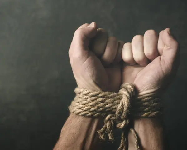 Związane dłonie, symbolizujące bezsilność i potencjalne naruszenie art. 189a kk.
