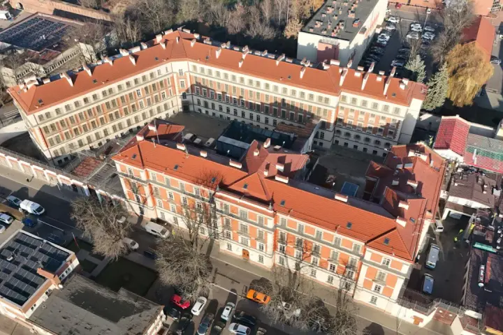 Widok z lotu ptaka na budynki więzienia aś montelupich. Czerwone dachy, białe fasady, dziedziniec z samochodami i drzewami.