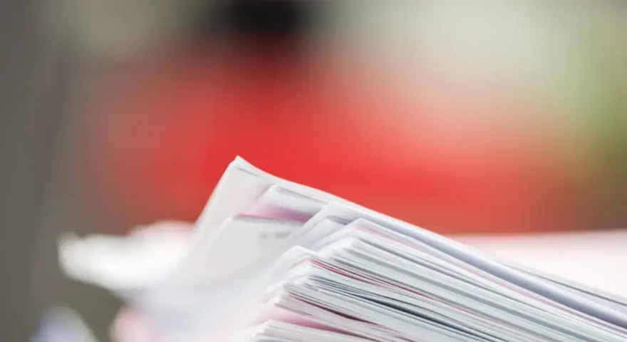 Stos dokumentów, potencjalne dowody rzeczowe w postępowaniu karnym, z czerwonym tłem.