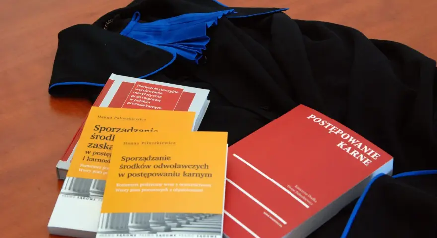 Książki o prawie karnym i togi prawnicze. Wiedza o prawach przysługujących oskarżonemu w sądzie jest kluczowa.
