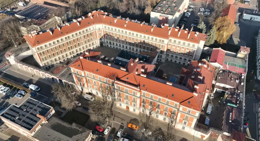 Widok z lotu ptaka na zakład karny Montelupich. Widać budynki z czerwonymi dachami, ogrodzenie z drutem kolczastym i parking. Odwiedziny w zakładzie karnym.