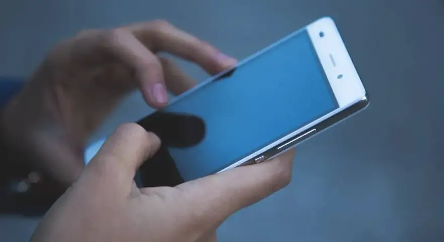 Dłonie trzymają biały smartfon. Czy na dołku można mieć telefon? Tak, nawet w trudnych chwilach można pozostać w kontakcie.