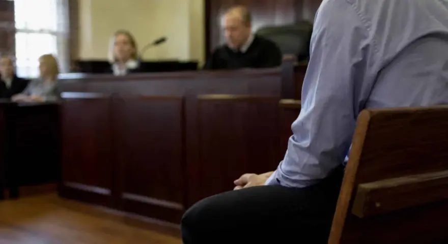 Osoba siedzi w ławie sądowej, czekając na decyzję w sprawie zgodnej z art. 37a. Sąd obraduje.