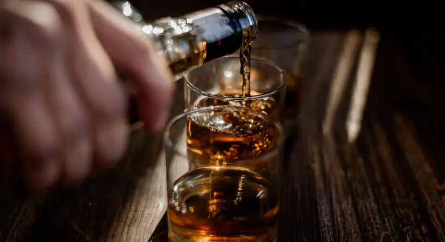 Nalewanie alkoholu do szklanek. Ta scena może symbolizować sprawę w sądzie za picie alkoholu przez nieletnich.