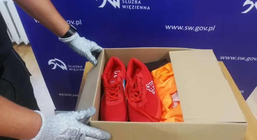 Rękawiczki przygotowują paczkę z czerwonymi butami i pomarańczową odzieżą. To wzór talonów dla osadzonych.